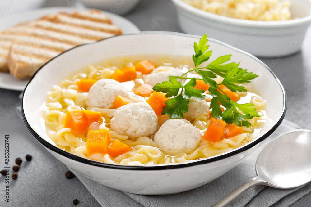 Hot chicken soup, broth with meatballs, carrot, pasta and fresh parsley Hot chicken soup, broth with meatballs, carrot, pasta and fresh parsley