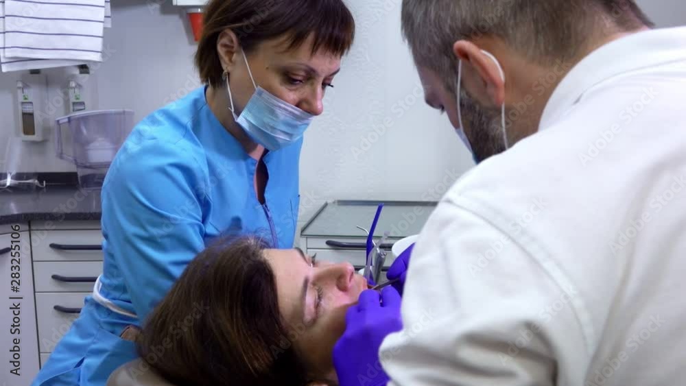 Dentist examines a patient's oral cavity with an assistant Dentist examines a patient's oral cavity with an assistant