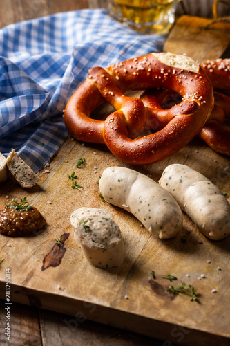 White german sausage, brezel, mustard and beer. Oktoberfest food. Traditional bavarian white sausage in beer gaten on wooden table.