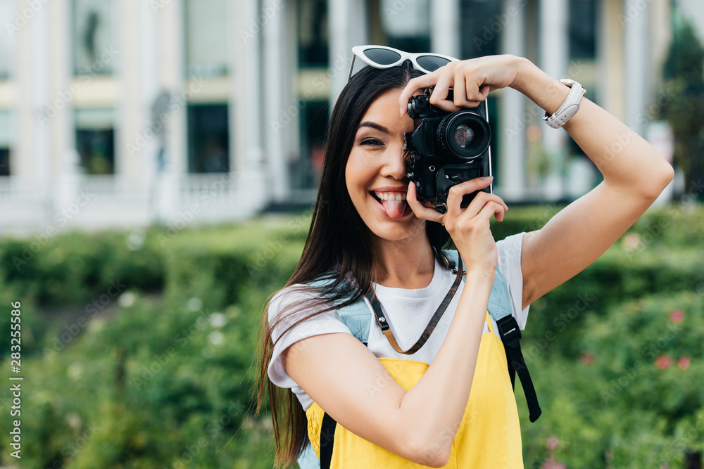 attractive and asian woman with glasses sticking out tongue and taking photo