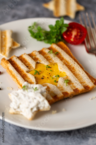 Toast with scrambled eggs in the shape of star with cheam cheese and vegetables. Christmas breakfast. Funny food.