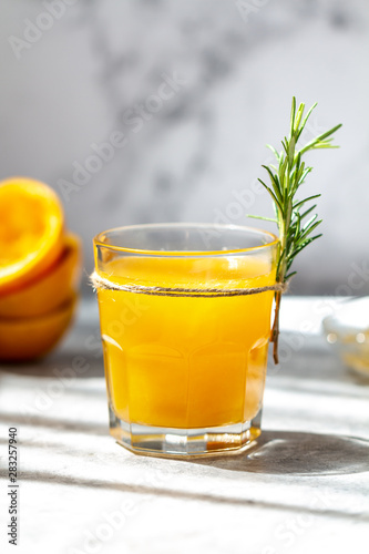 Glass of freshly pressed orange juice with orange squeezed halves on the table