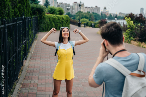man taking photo and asian woman showing yes gesture