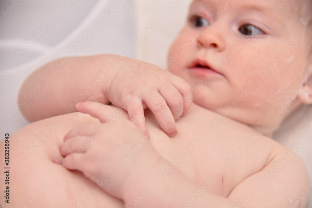 Pretty three months baby girl taking a bath by her mother at home, european child. Pretty three months baby girl taking a bath by her mother at home, european child.