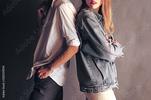 Happy Young Couple Back To Back Each Other on a Grey Wall Background. .Couple ignoring each other while standing back to back