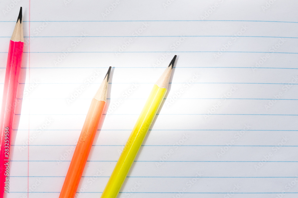 Blank notebook and pencils on white background. School supplies. White sketch book with colourful pencils. Note book and pencil