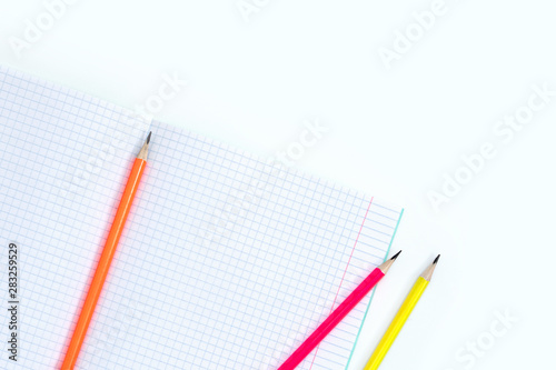Blank notebook and pencils on white background. School supplies. White sketch book with colourful pencils. Note book and pencil
