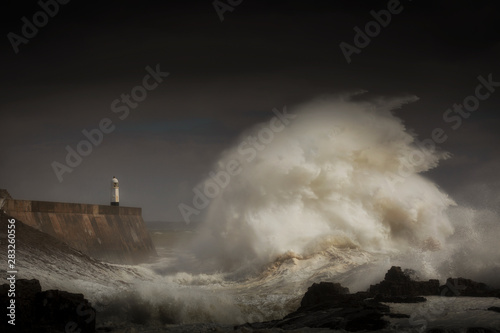 Porthcawl lighthouse and pier in the jaws of a storm on the coast of South Wales, UK.
