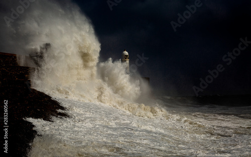 Porthcawl lighthouse and pier in the jaws of a storm on the coast of South Wales  UK.