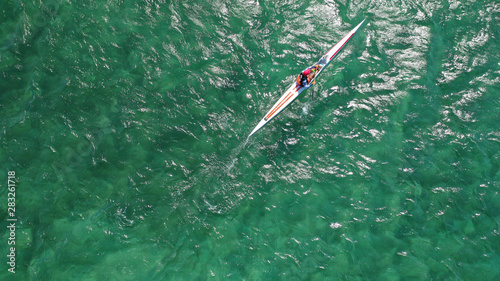 Aerial drone photo of young man practising sport canoe in tropical exotic bay with calm emerald open ocean sea