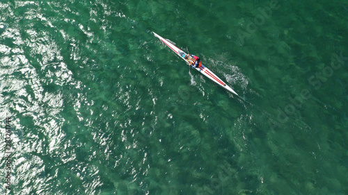 Aerial drone photo of young man practising sport canoe in tropical exotic bay with calm emerald open ocean sea