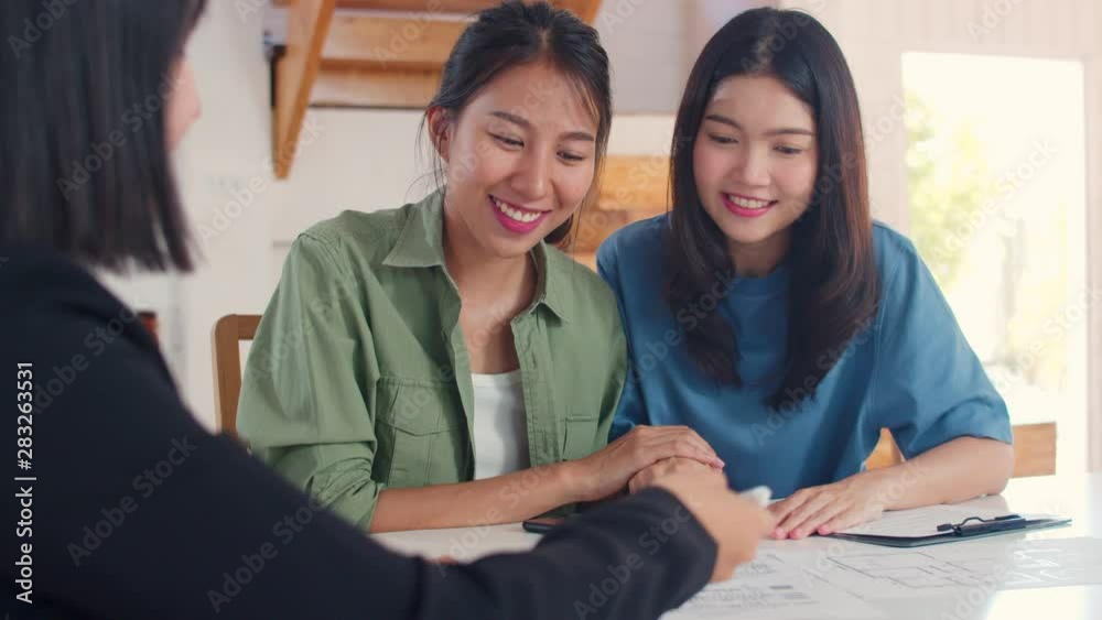 Asian Lesbian lgbtq women couple sign contract at home, Young couple consulting with real estate financial advisor, Buying new house and handshaking with broker in living room concept. Asian Lesbian lgbtq women couple sign contract at home, Young couple consulting with real estate financial advisor, Buying new house and handshaking with broker in living room concept.