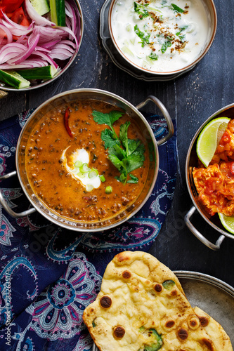 Indian curry meal with black lentils dal, spicy potatoes, rice, naan bread and raita