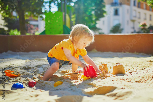 little girl having fun on playground in sandpit photo