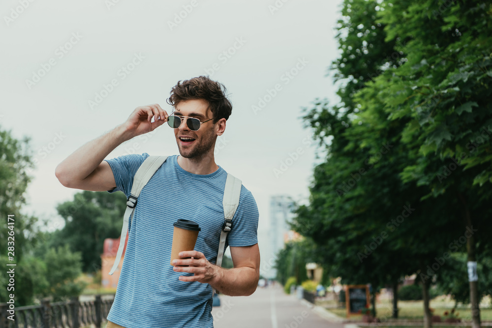 handsome man in t-shirt holding paper cup and looking away