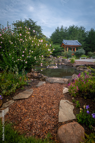 Pagoda and Pond on a Misty Morning with Hibiscus Flower Bush and Stone Lined Walking Path