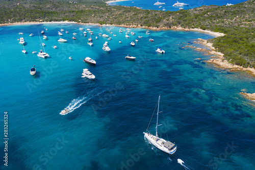 View from above  stunning aerial view of a beautiful bay full of boats and luxury yachts. A turquoise sea bathes the green and rocky coasts. Liscia Ruja  Emerald Coast  Costa Smeralda  Sardinia  Italy