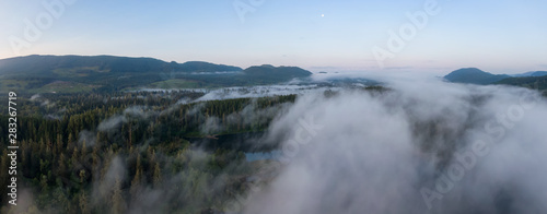 Aerial Panoramic View of Fairy Lake covered in clouds during a vibrant summer sunrise. Taken near Port Renfrew, Vancouver Island, British Columbia, Canada.