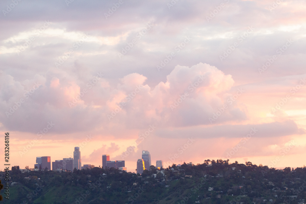 hillside view of homes with downtown towers under baby pink, lavender and blue sunset