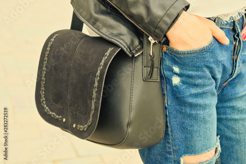Young woman hold yoyr hand in pocket wih black handbag on her shoulder