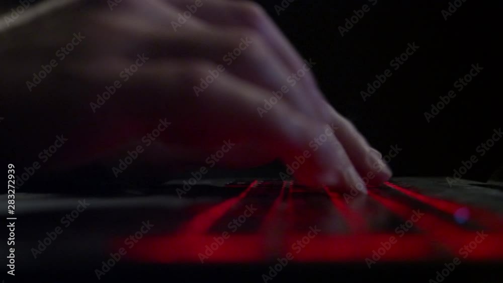 Man typing on the notebook keybord. Hacker hands typing in the dark room. Pan left to right. Close up shot. Man typing on the notebook keybord. Hacker hands typing in the dark room. Pan left to right. Close up shot.