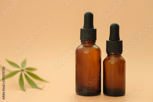 Dark glass bottles with full, cannabidiol oil and hemp leaves on a pastel background. Health conception. Medical marijuana.