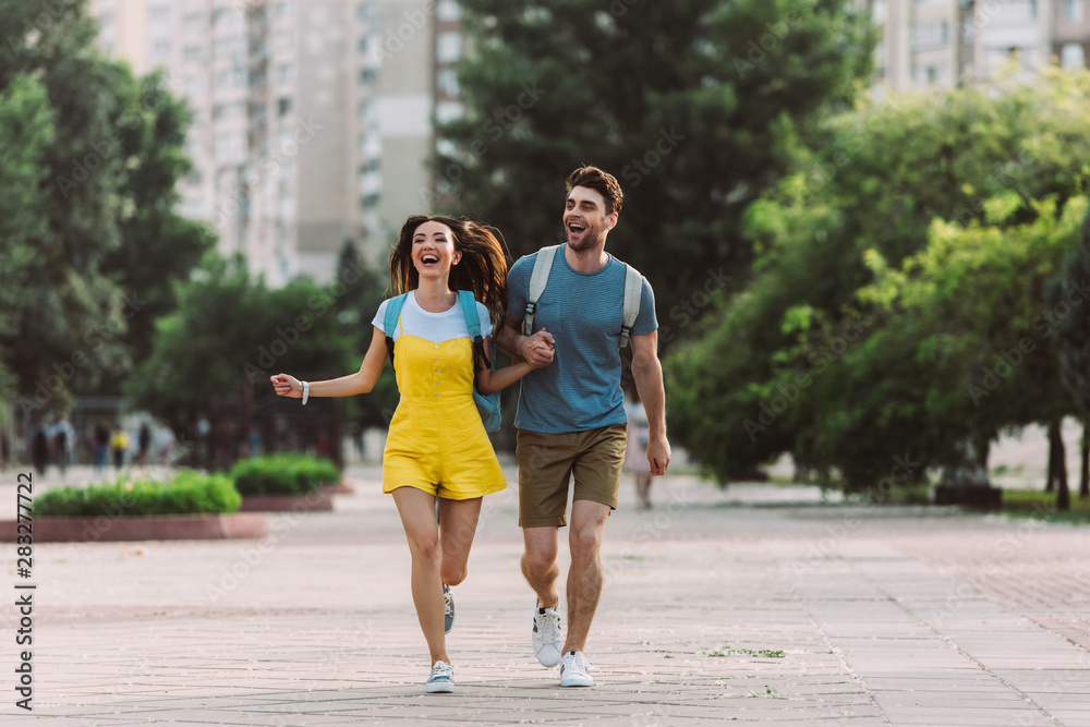 handsome man and asian woman running and looking away
