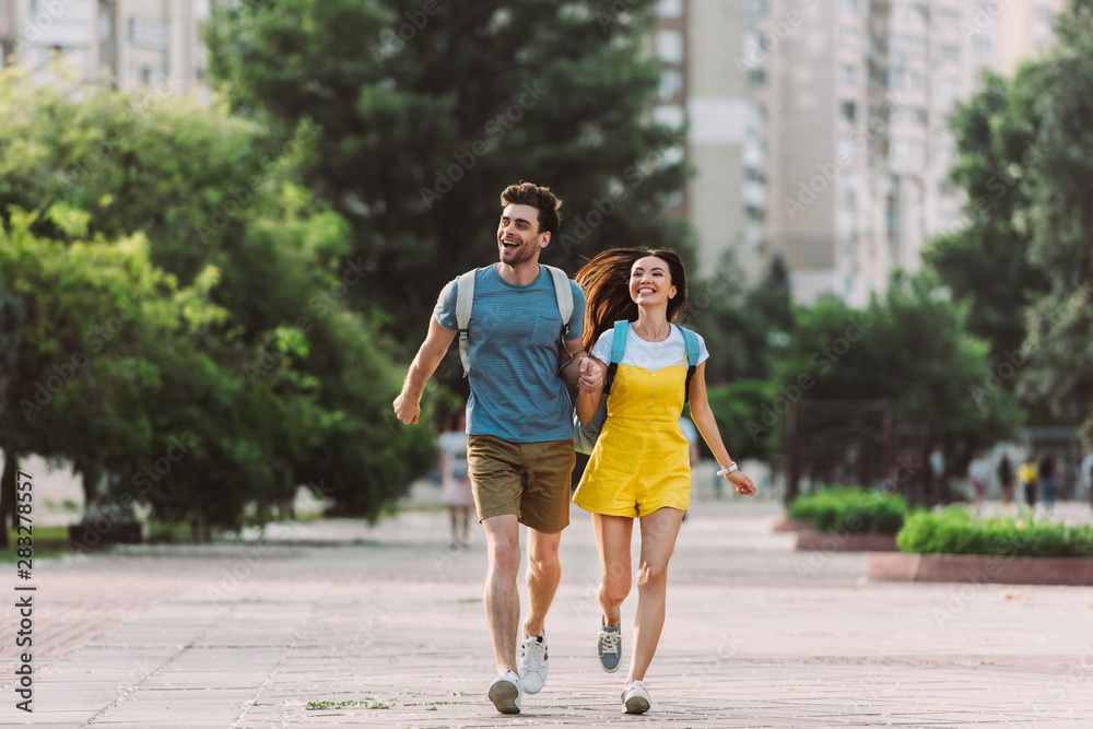 handsome man and asian woman running and looking away
