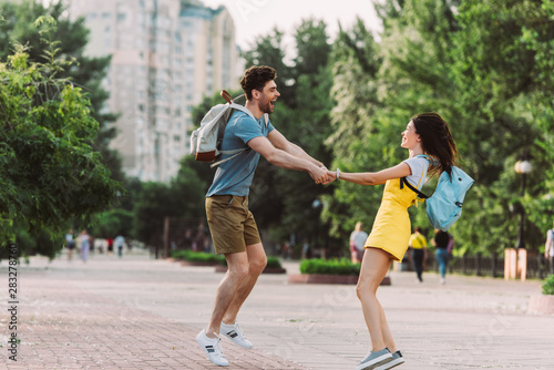 handsome man and asian woman smiling, jumping and holding hands