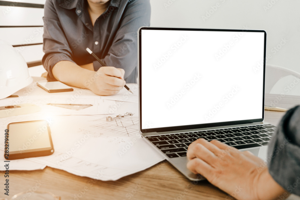 Fototapeta premium Mockup image of engineers using laptop to drawing design building Project in office, mockup concept