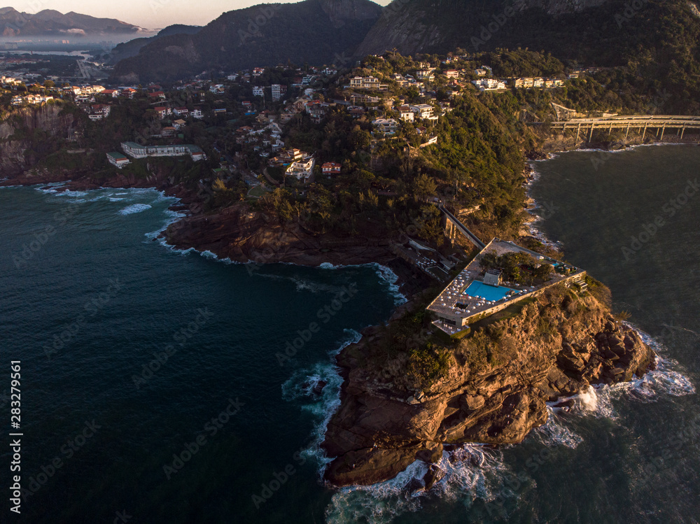 Panoramic view of the coastline of Joatinga in Rio de Janeiro with its beautiful picturesque natural richness and Costa Brava social club with pool in the foreground on a small island at dawn