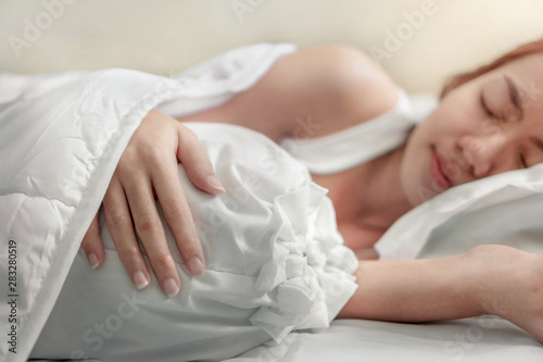 Young asian woman sleeping alone on white pillow on bed in bedroom on morning time.