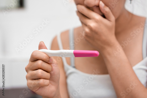 Young asian woman holding pregnancy test and shocked with result in her bathroom  wellness and healthy concept  infertility problem  Selective focus.