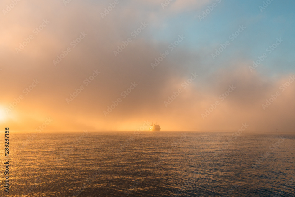 Ferry on the water horizon going through the fog.