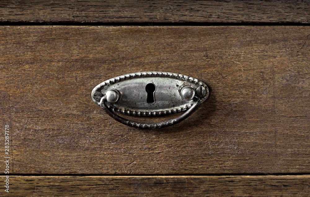Metal door knob on a wooden old drawer. Dark brown wooden background Metal door knob on a wooden old drawer. Dark brown wooden background
