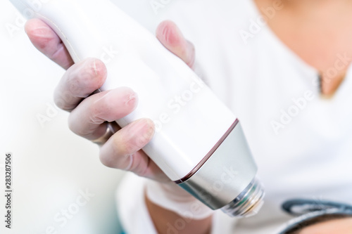 Beautician holding radio frequency microneedling hand piece. Used for skin tightening and cosmetic treatments in spas, salons and laser clinics.