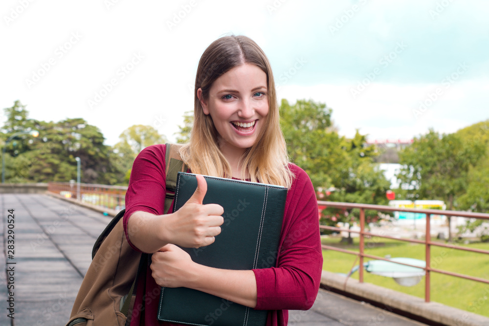 Young female student with folders in college campus. Young female student with folders in college campus.