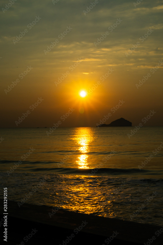 The tropical sea, sunset, has an island in the back. Clear orange sky .