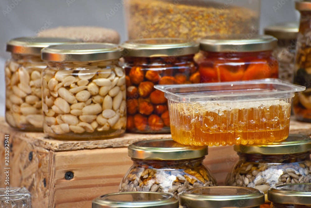 Lots of assorted honey on the table. Jars of sweets are sold at the fair. Honey with different kinds of nuts then dried fruits. Lots of assorted honey on the table. Jars of sweets are sold at the fair. Honey with different kinds of nuts then dried fruits.