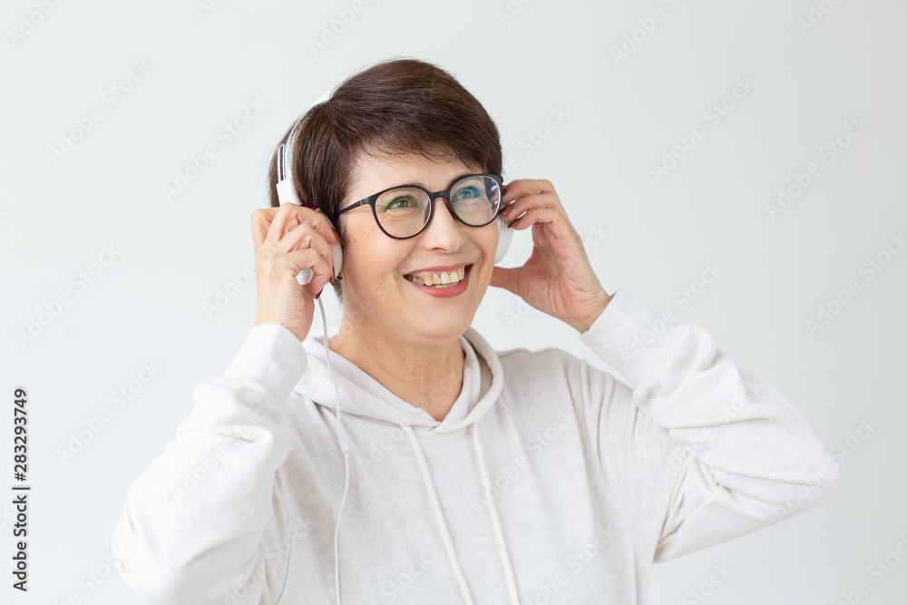 Hobby, interests and people concept - Beautiful woman 40-50 years old listening music in big headphone on white background Hobby, interests and people concept - Beautiful woman 40-50 years old listening music in big headphone on white background