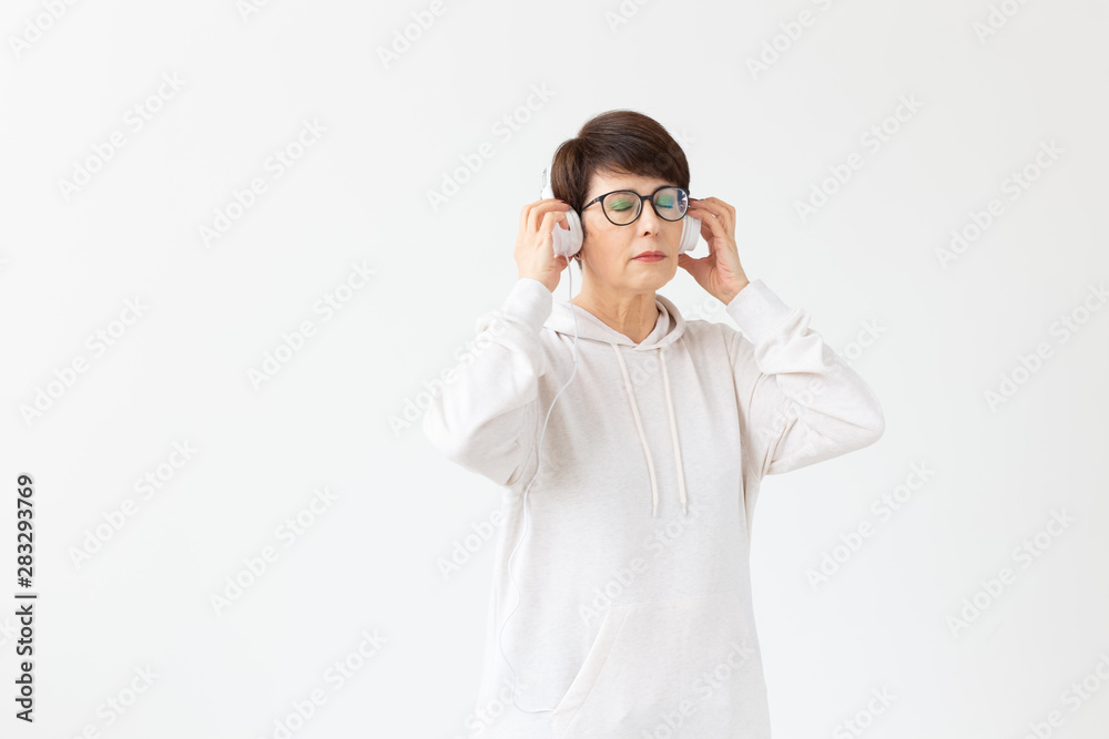 Hobby, interests and people concept - Beautiful woman 40-50 years old listening music in big headphone on white background with copy space Hobby, interests and people concept - Beautiful woman 40-50 years old listening music in big headphone on white background with copy space