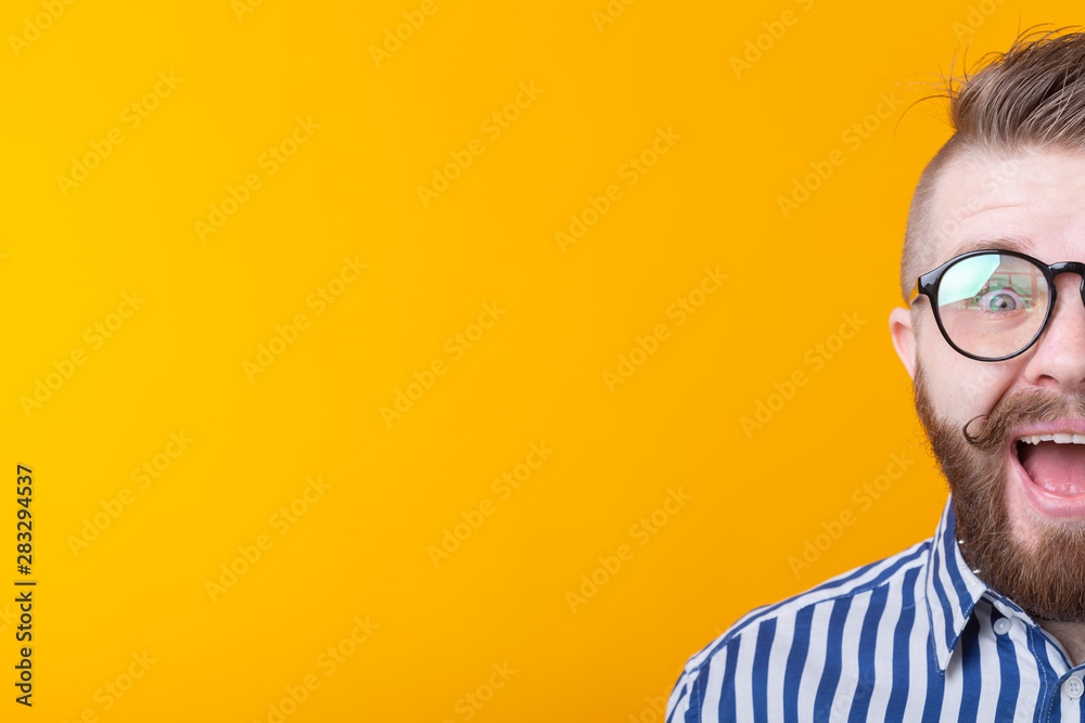 Stylish young hipster man with a mustache and beard joyfully opens his mouth on a yellow background with copy space. Concept of surprise and celebration. Stylish young hipster man with a mustache and beard joyfully opens his mouth on a yellow background with copy space. Concept of surprise and celebration.