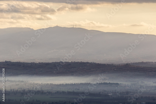 Mist filling a valley in Umbria (Italy) at sunet, with layers of mountains and hills and warm colours