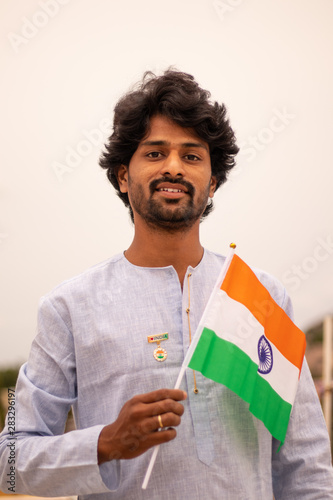 Portrait of a Young Indian man holding Indian flag in traditioanal Indian dress. photo