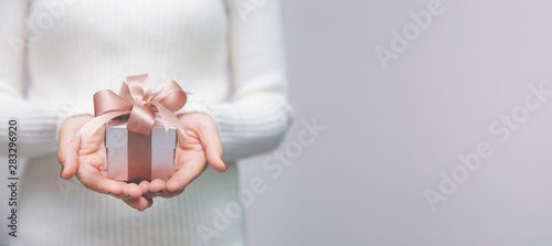 Woman hands with white sweater holding a small gift box for special event with copy space.