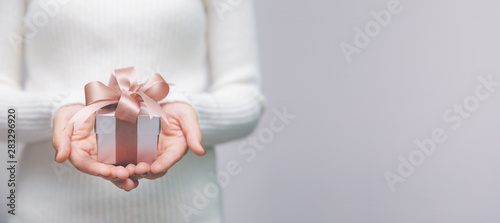 Woman hands with white sweater holding a small gift box for special event with copy space. photo