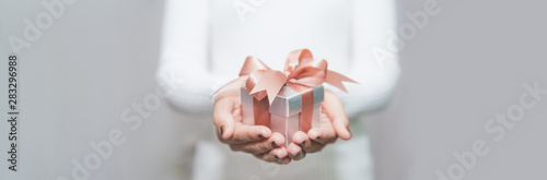 Woman hands with white sweater holding a small gift box for special event with copy space.