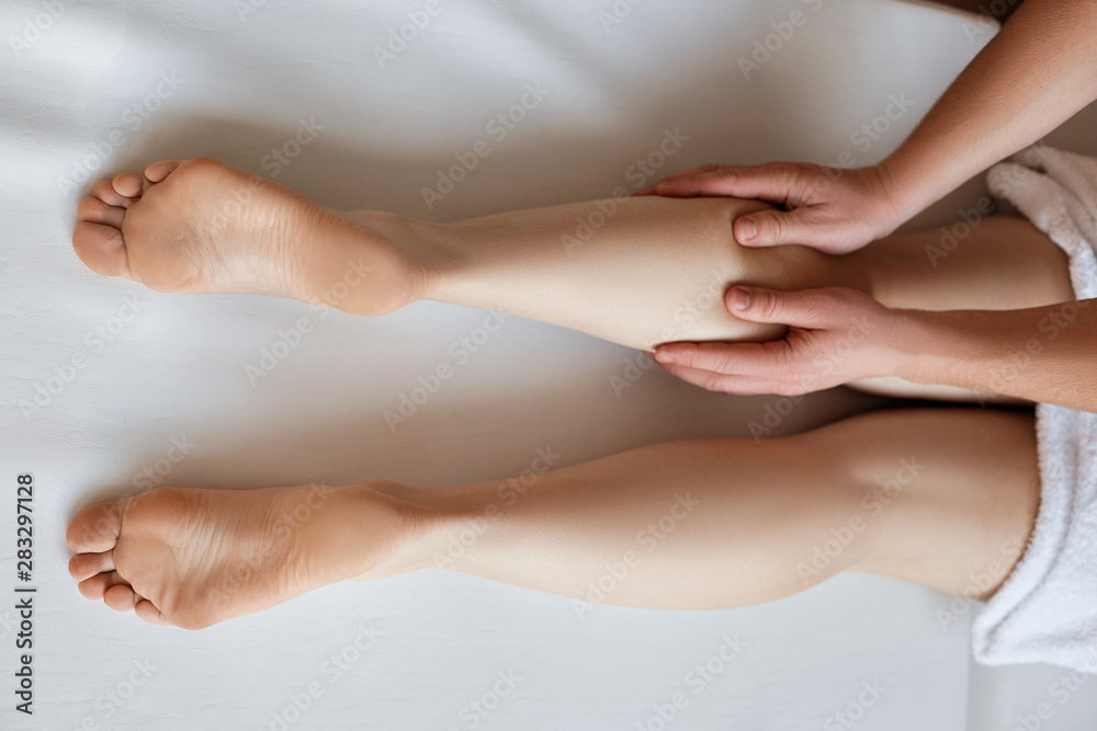 Massaging tired muscles. Close-up of massage therapist massaging beautiful female leg. Cosmetology and spa treatments