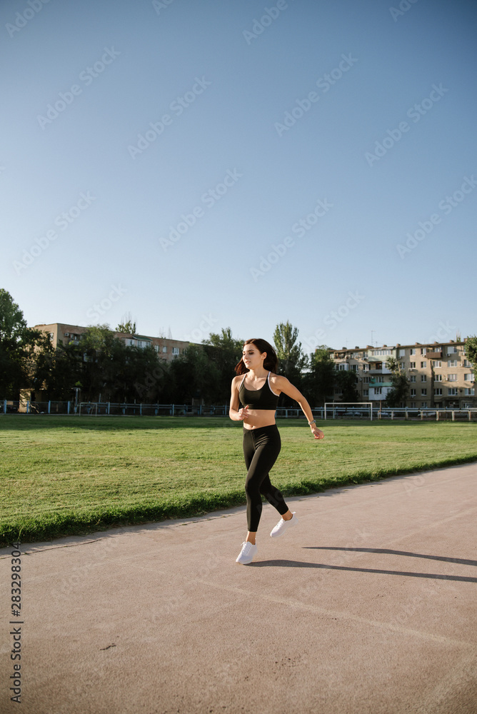 Young woman running during sunny morning on stadium track Young woman running during sunny morning on stadium track