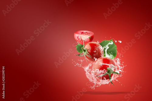 Water splashing on Fresh Red Tomatoes over red background © kaiskynet